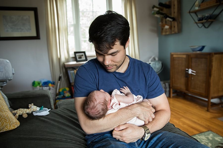 dad with newborn sitting on couch of pittsburgh home for newborn photo session