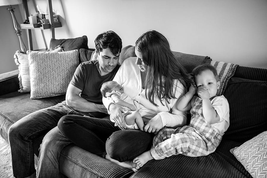 family with toddler and newborn sitting on couch of pittsburgh home for newborn photo session