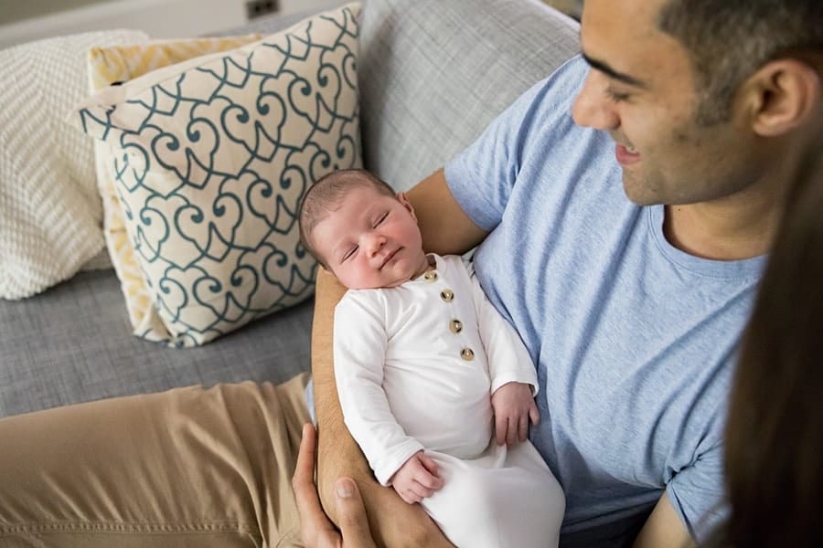 dad holds sleeping newborn baby on couch of pittsburgh home