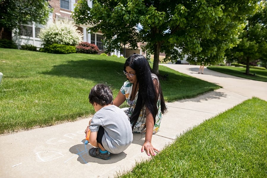 mother and son sitting on sidewalk