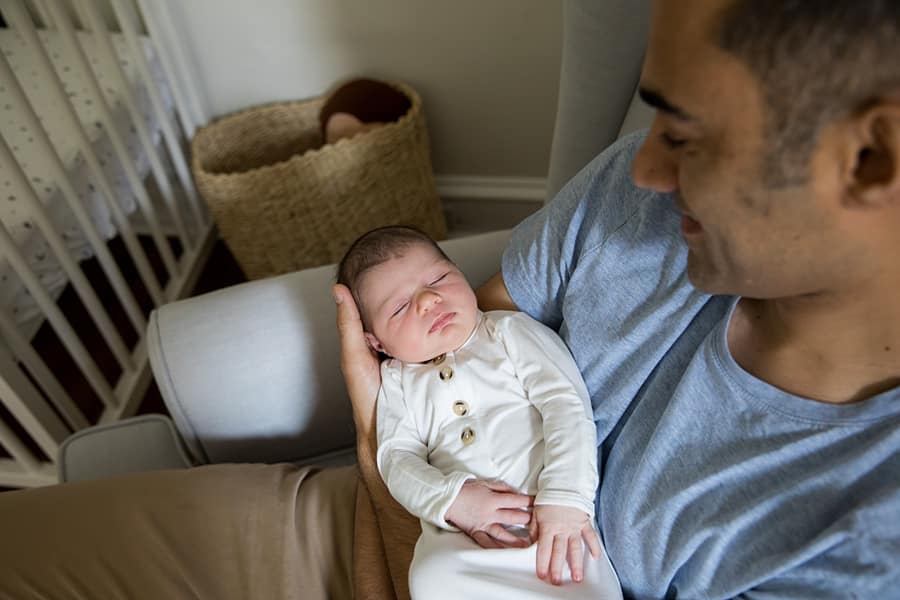 dad holds sleeping newborn baby in nursery of pittsburgh home