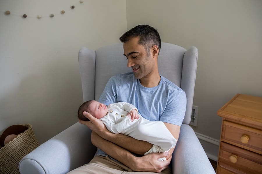 dad holds sleeping newborn baby in nursery of pittsburgh home