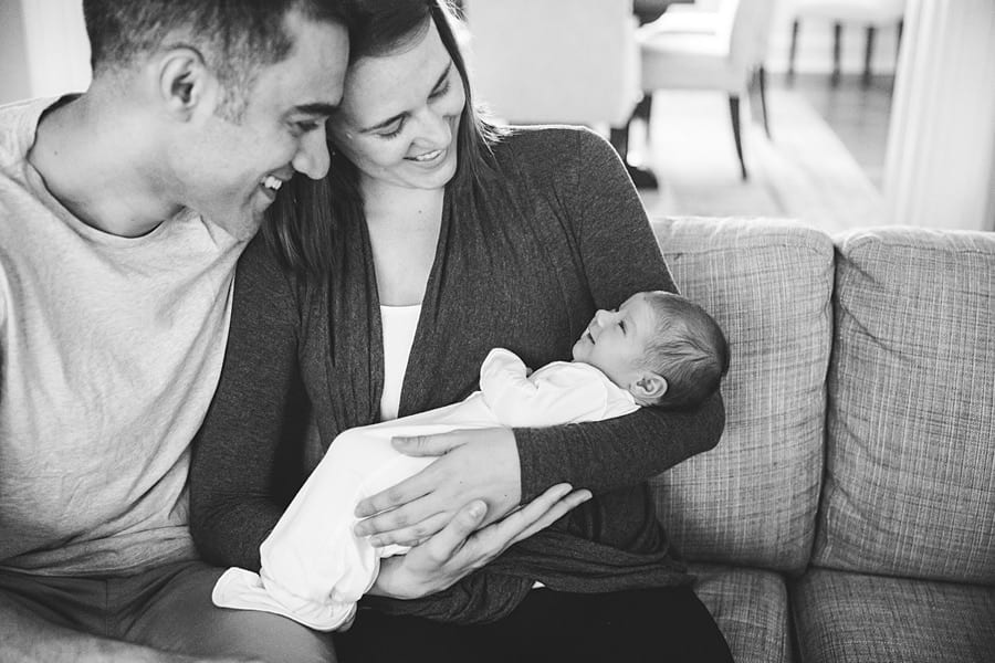 mom and dad hold newborn baby on couch of pittsburgh home Shadyside Newborn Photographer 