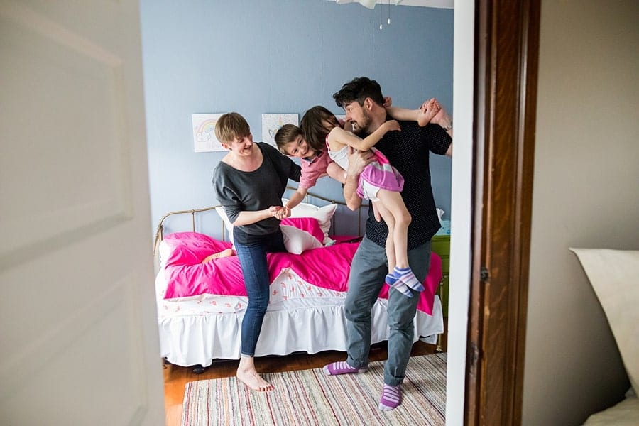 dad holding daughter and son in bedroom with mom