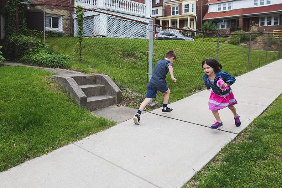 brother and sister running in front of pittsburgh home on sidewalk Family Photographer in Point Breeze Pittsburgh