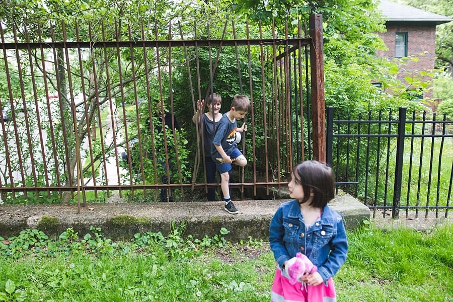 brother and sister squeezing through iron fence Family Photographer in Point Breeze Pittsburgh