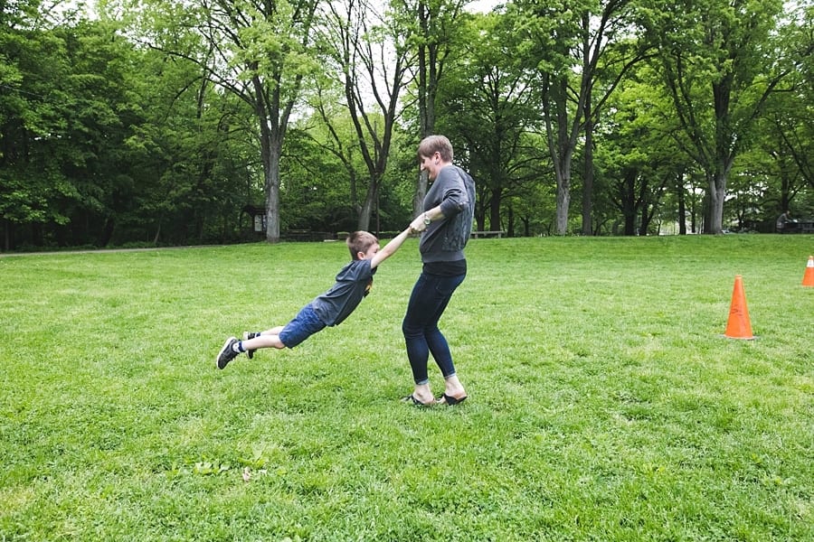 mom spinning son in green grass at frick park pittsburgh