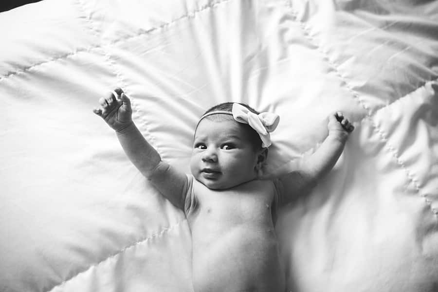 awake stretching newborn baby on bed of pittsburgh home Shadyside Newborn Photographer