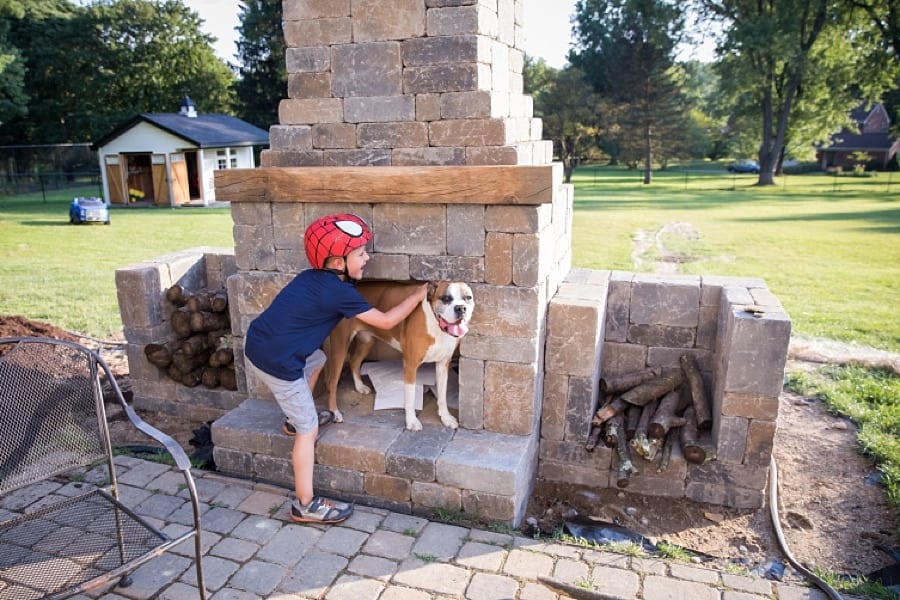boy and dog standing on patio fireplace