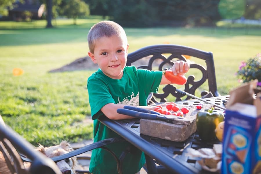 boy holds a tomato on the patio porch table