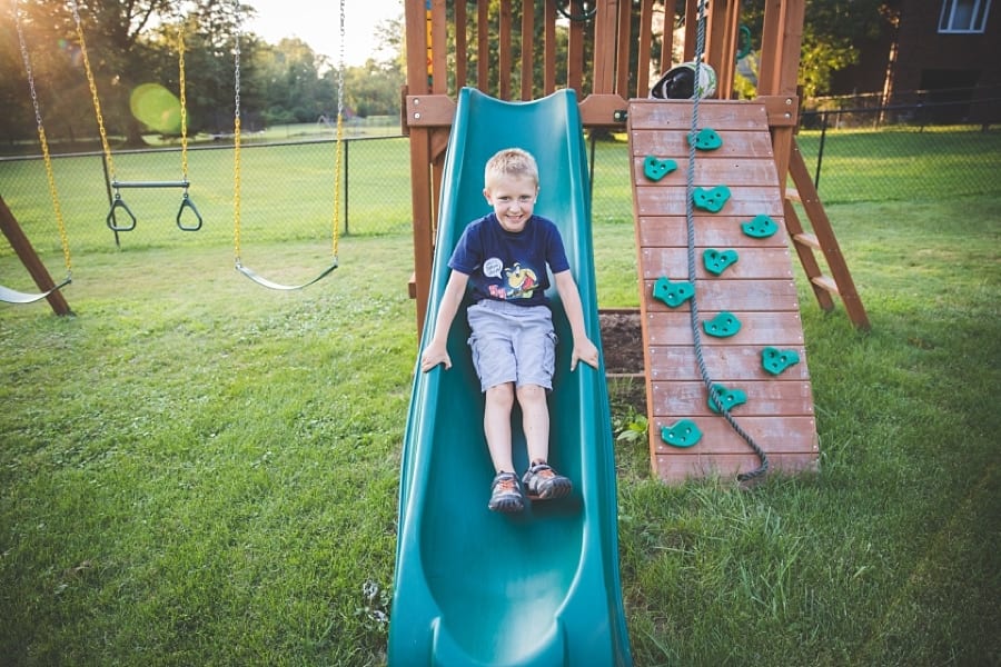 boy slides down play swing set in pittsburgh backyard