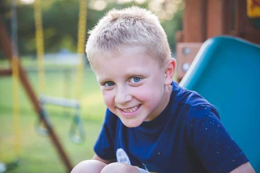 boy smiling on slide in pittsburgh backyard