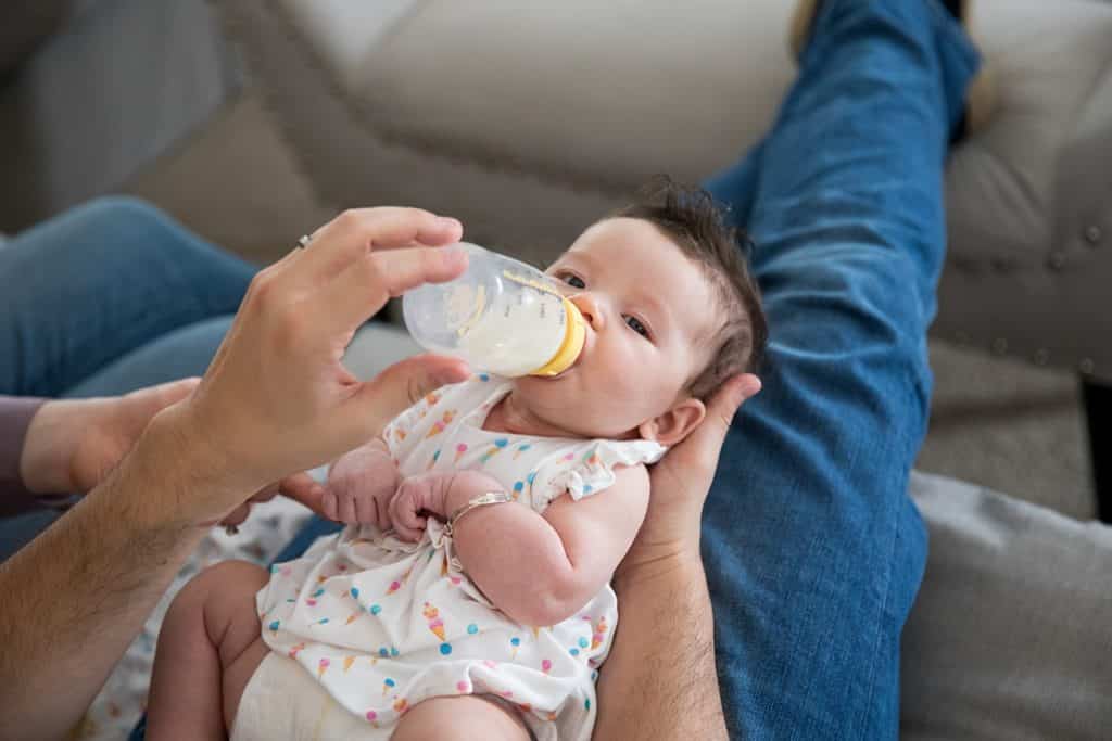 dad feeding baby a bottle on the couch