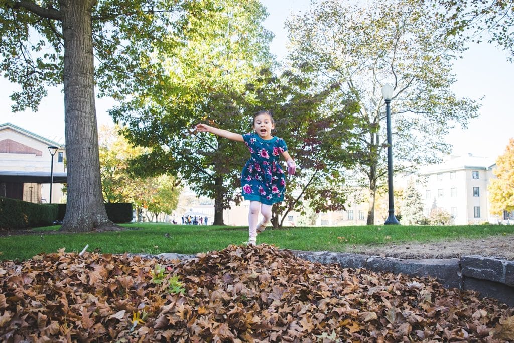girl jumping in fall leaves for phot o session at at carnegie mellon campus pittsburgh