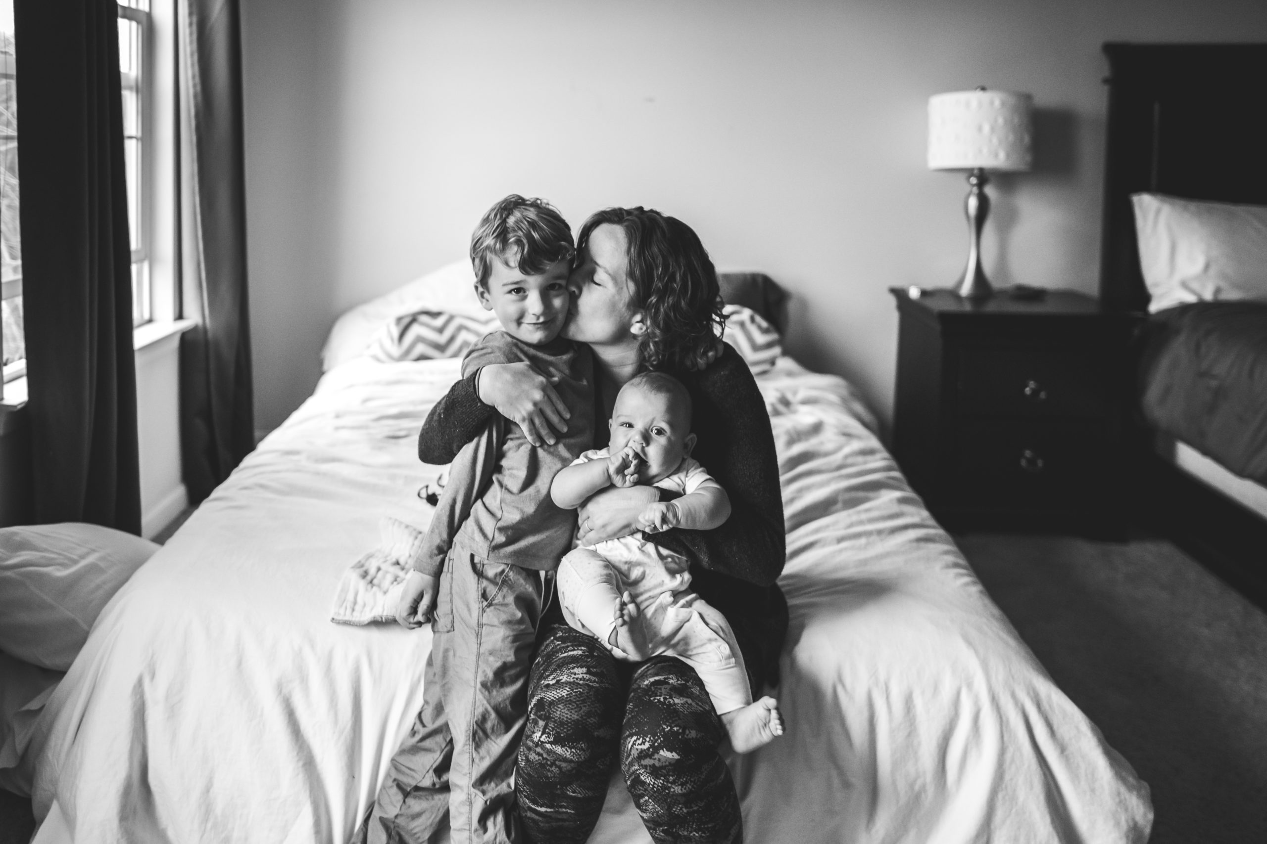 mom and sons sitting on bed for at home photo session