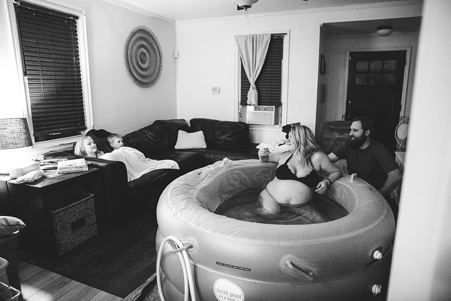 mom in birthing pool in living room with husband and children for homebirth
