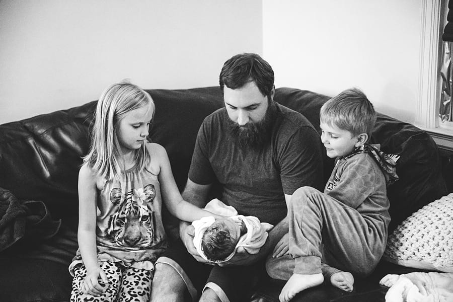 father introducing newborn baby to siblings after home birth