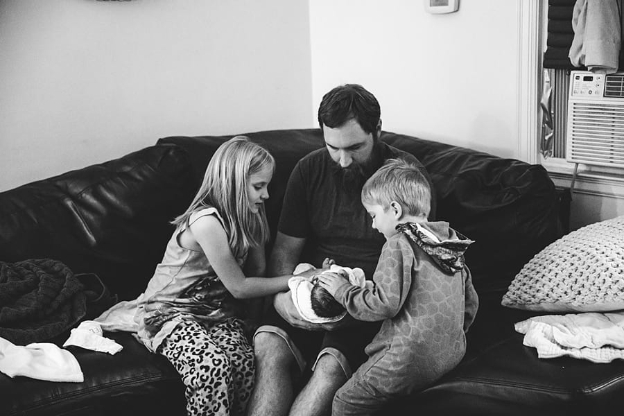 father introducing newborn baby to siblings after home birth