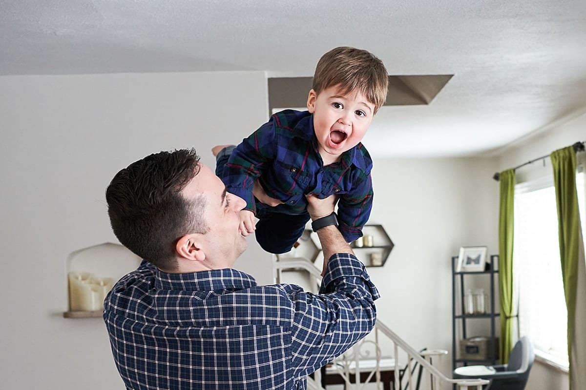 dad holding toddler in air in house