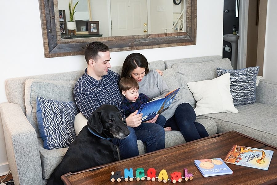 mom dad and toddler son on couch for a lifestyle family photo session with family dog