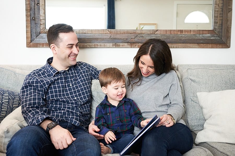 mom dad and toddler son on couch for a lifestyle family photo session with family dog