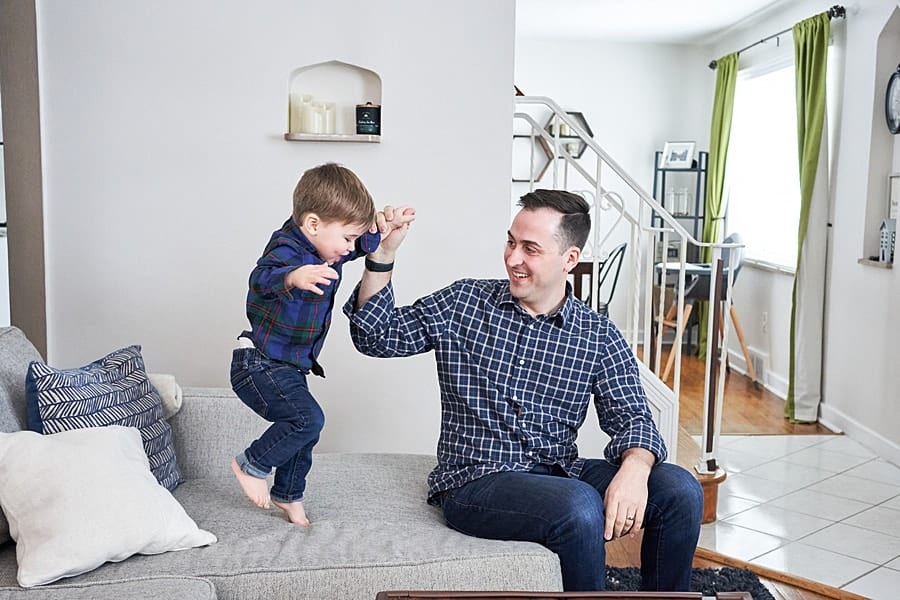 dad and toddler son jumping on couch for a lifestyle family photo session