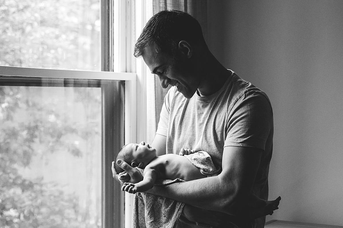 dad holding newborn baby in pittsburgh nursery window light