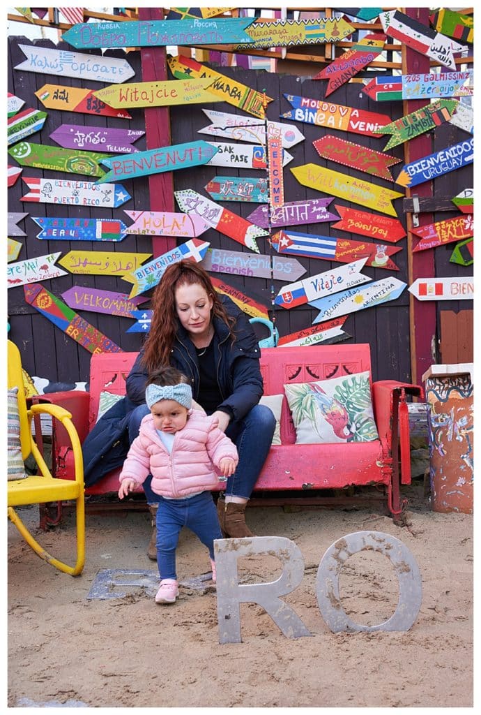 photo session at randlyland with toddler and mom on a vintage pink glider with colorful signs