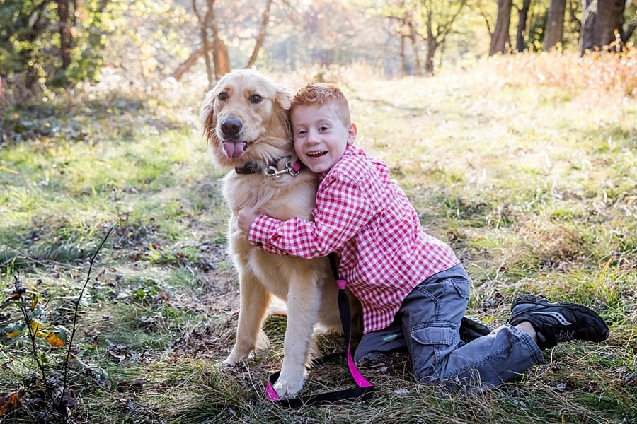 red headed boy hugs golden retriever dog