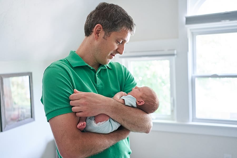 dad holding newborn son in nursery