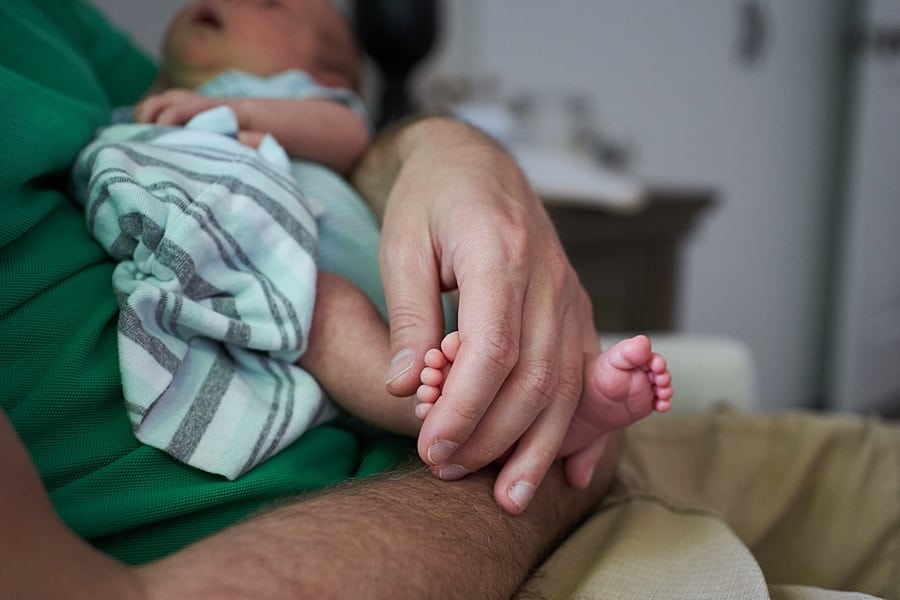 dad's hands around newborn sons feet