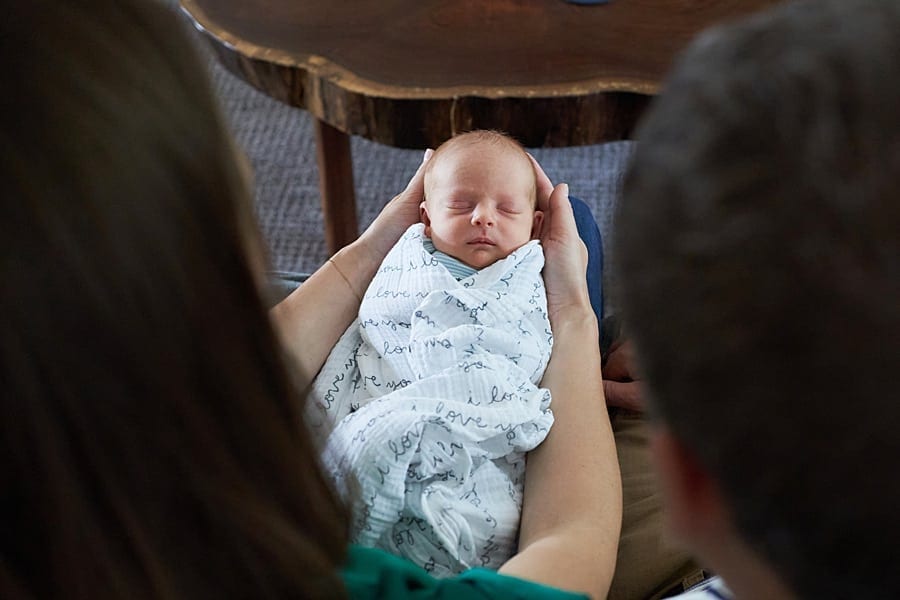 mom holding newborn son on living room couch