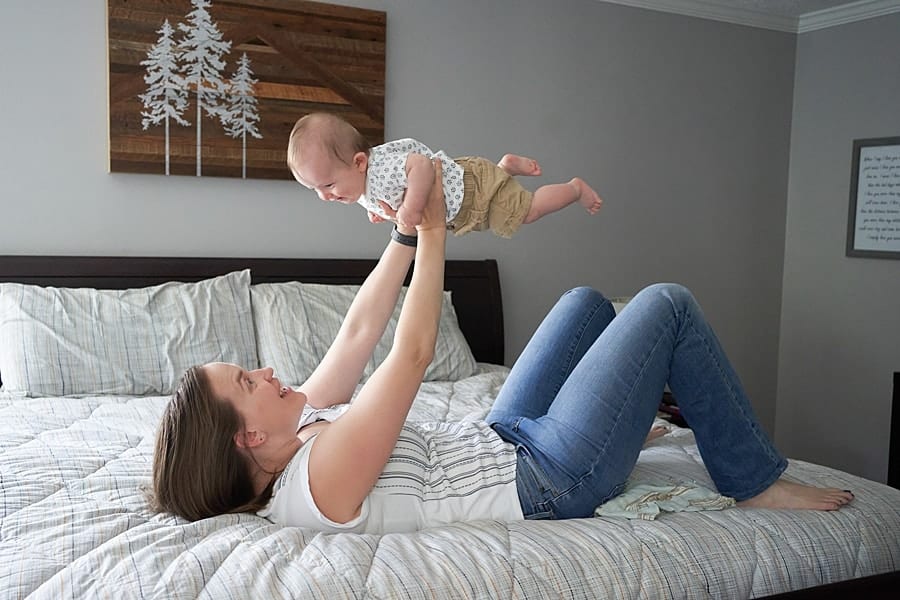 mom holding up baby boy in bedroom for photo session in pine township pa