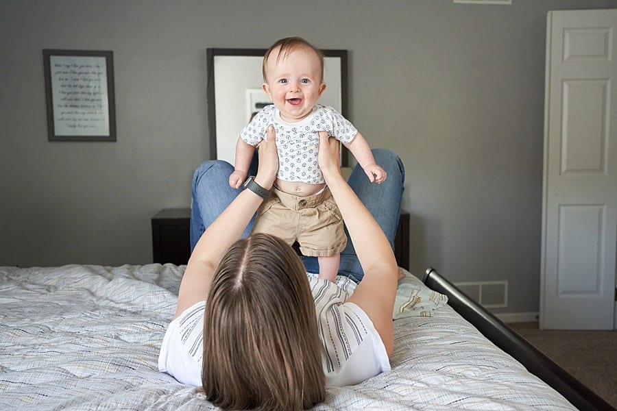 mom holding up baby boy in bedroom for photo session in pine township pa