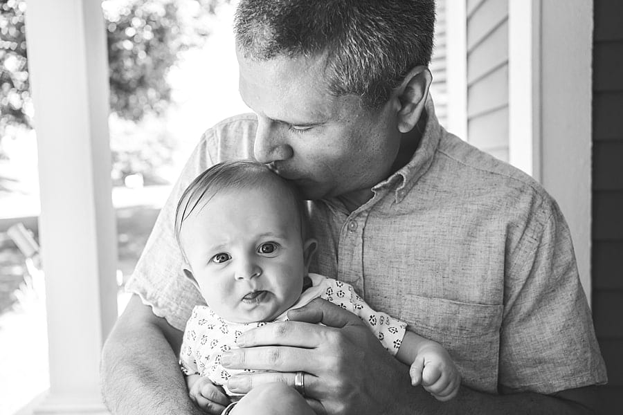 dad kissing baby boy in light outside for lifestyle photos