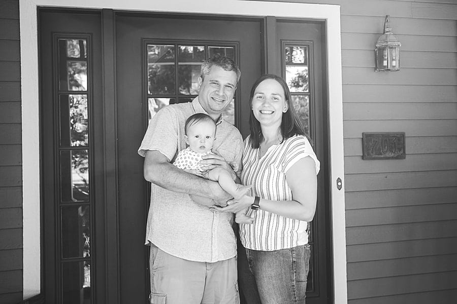 mom dad and baby pose on porch for lifestyle photo session at their pine township home