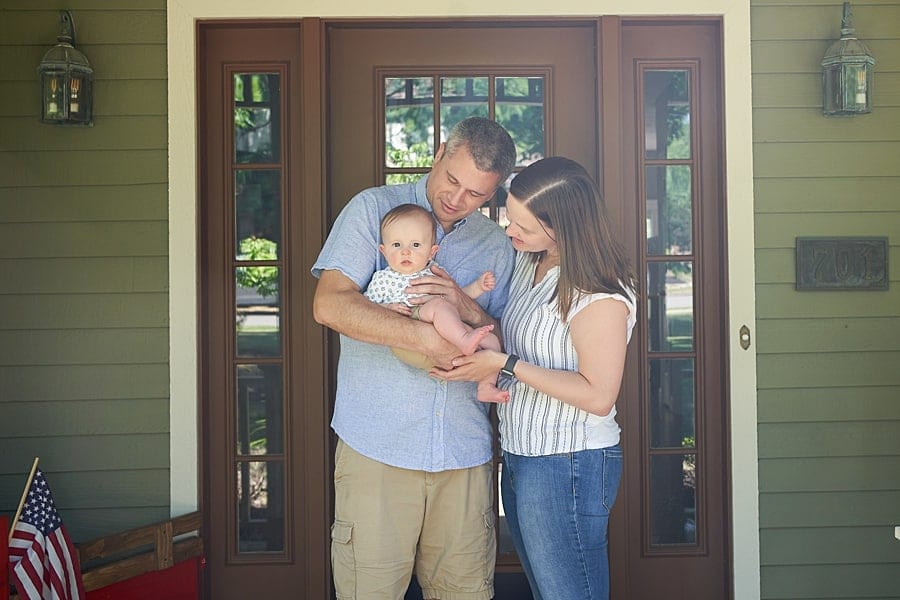 mom dad and baby pose on porch for lifestyle photo session at their pine township home
