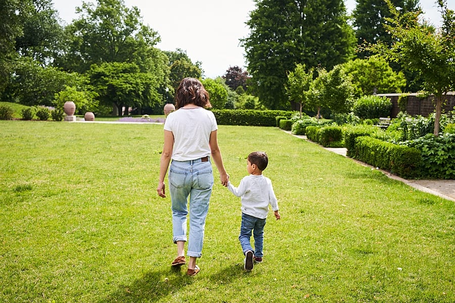 mom and son hold hands in grass at Mellon park