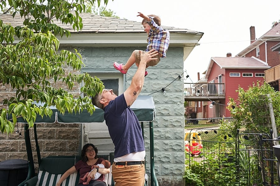 dad tossing son in the air in the backyard while mom watches