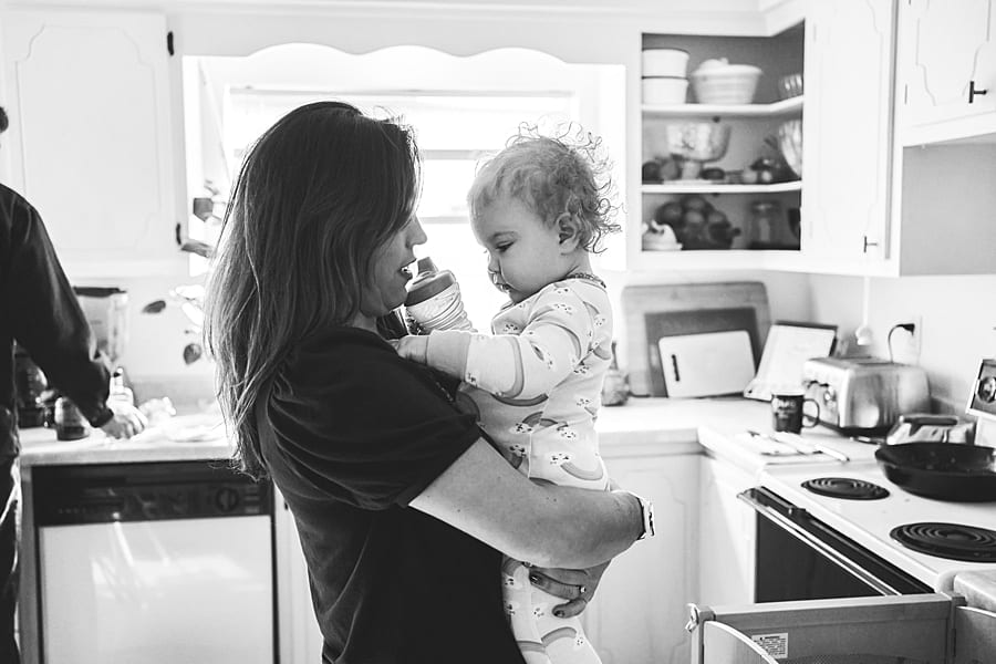 Mother holding daughter with chubby cheeks and sippy cup in their Pittsburgh kitchen