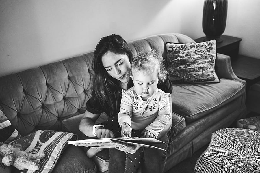 Mom reading a book to her daughter on their couch in Pittsburgh home