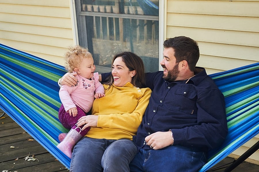 mom and dad holding daughter on hammock on pittsburgh porch