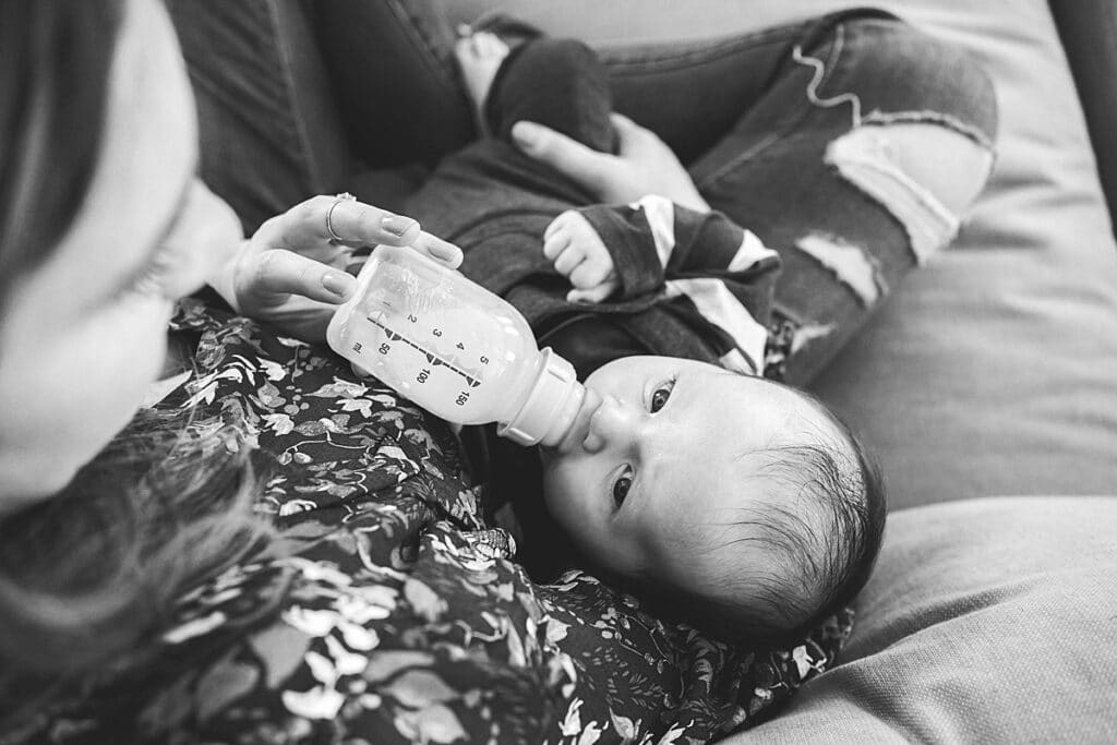 Mother feeding her baby boy with a bottle on the couch