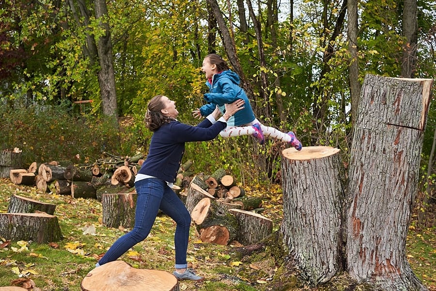 We're catching daughter jumping off of large tree stump in their backyard