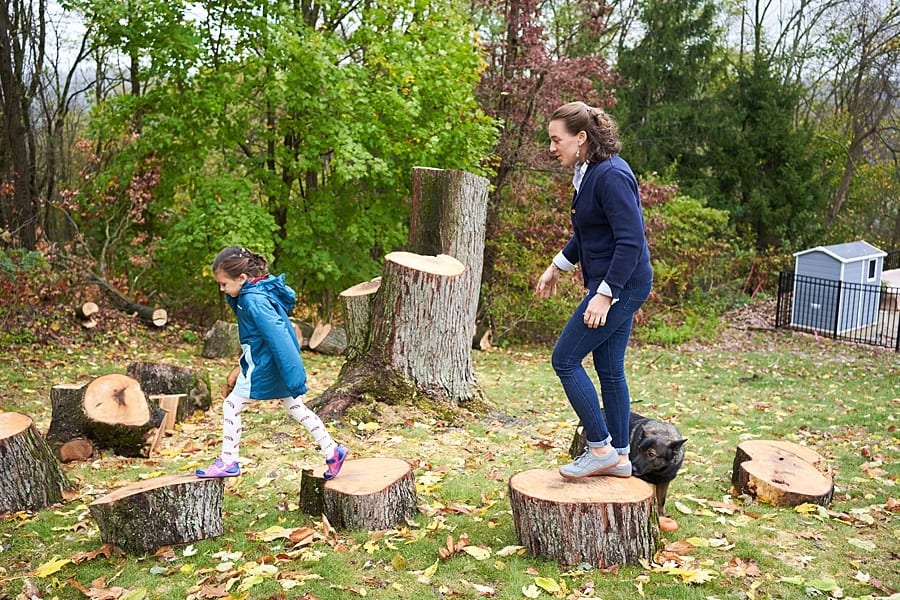 Mother and daughter walking on tree stumps in the backyard of their Pittsburgh home