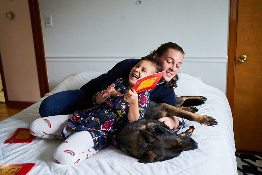Mother and daughter and service dog laying on bed together