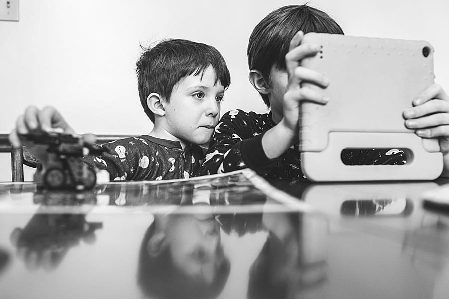 20 activities to do during your family session at home Brother sitting at the kitchen table looking at an iPad screen together