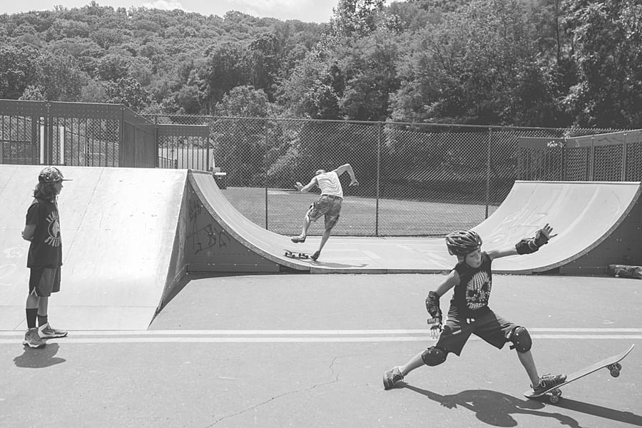 Boy doing a split falling on a skateboard with a man on a skateboard on a ramp behind him