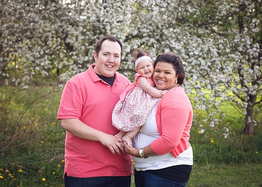 mom and dad with baby outside in the spring with blossoms at park for a family photo session in Youngstown ohio