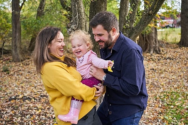 mom, dad, holding their laughing baby girl in pittsburgh yard for family photo session
